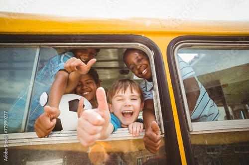 Cute mixed race pupils smiling at camera in the school bus