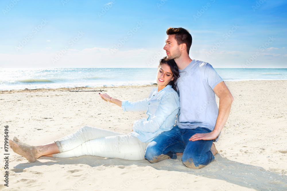 Couple relaxing on Sand at the Beach looking the sea