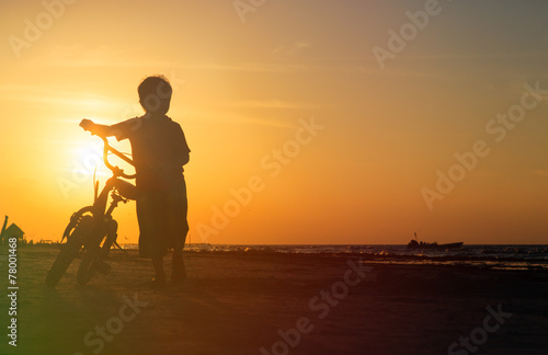 little boy riding bike at sunset