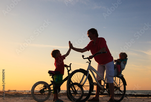 father with kids biking at sunset