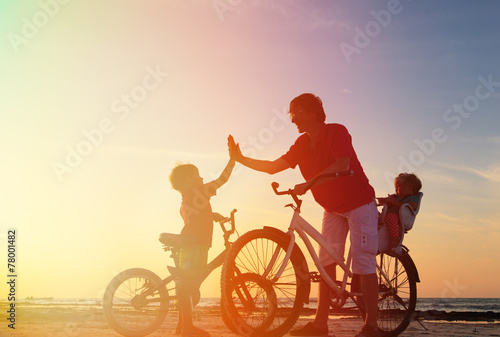 father with kids biking at sunset