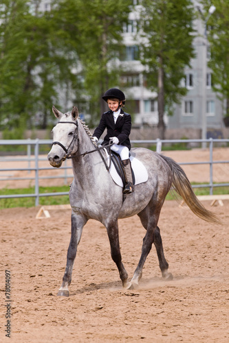 Little girl riding a horse participates in competitions