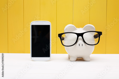 Piggy bank wearing glasses with cellphone