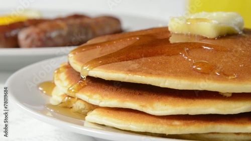 Closeup of syrup pouring onto pancakes