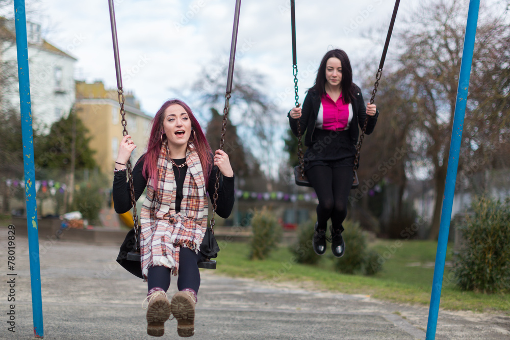 Two Teenage Girls Swinging on Swings