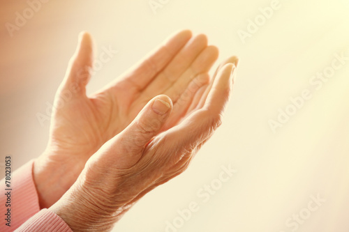 Hands of old woman on light background