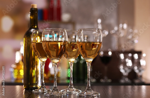 Glasses of wine on counter and bar on background