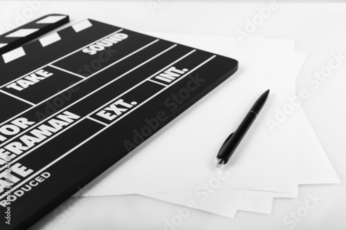 Movie clapper with sheets of paper and pen on white background