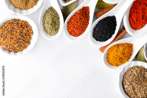 Different kinds of spices in ceramics bowls and spoons isolated