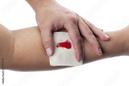 human hand holding bandage on wrist with blood on it