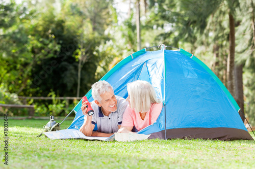 Senior Couple With Map And Torch In Tent