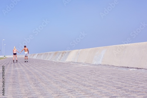 Fit couple rollerblading on the promenade