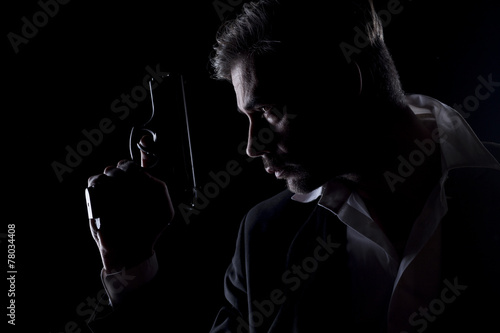 Profile of men's silhouette in the dark with a gun in his hand