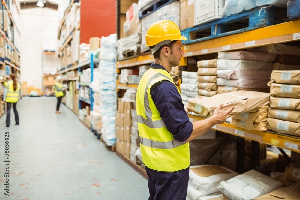 Warehouse worker taking package in the shelf Warehouse worker taking package in the shelf