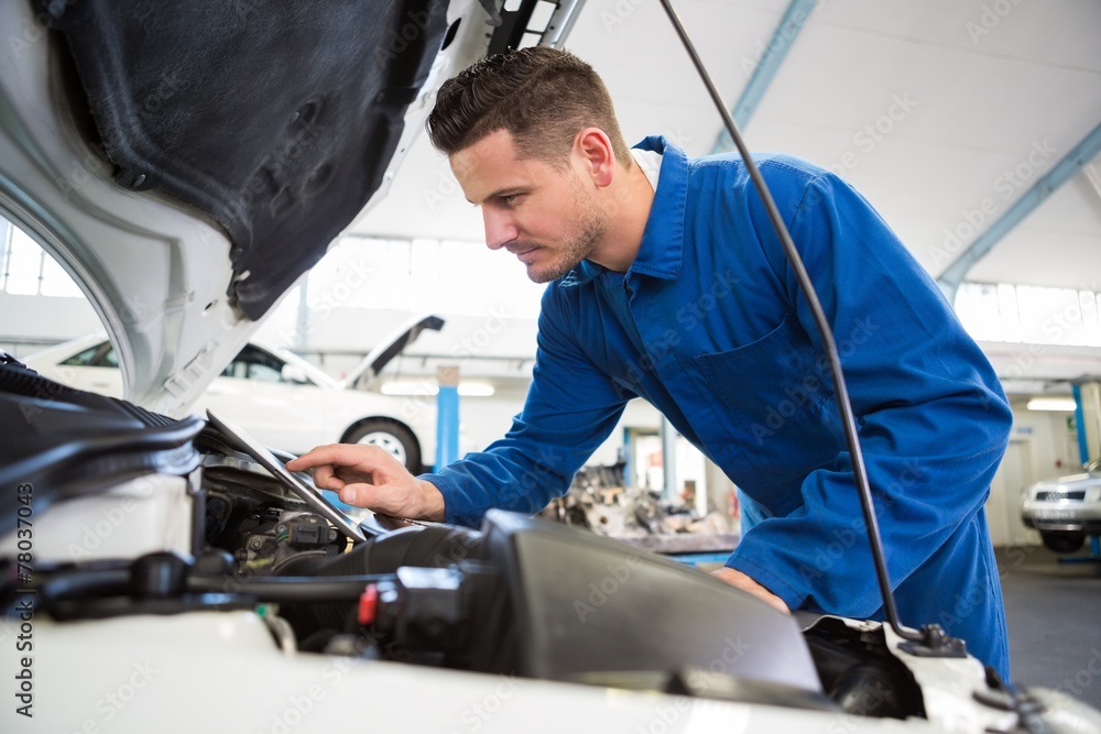 Mechanic using tablet to fix car Mechanic using tablet to fix car