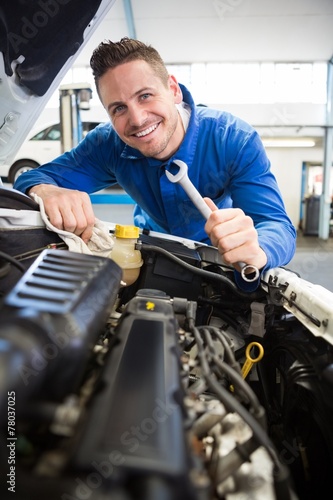Mechanic smiling at the camera fixing engine