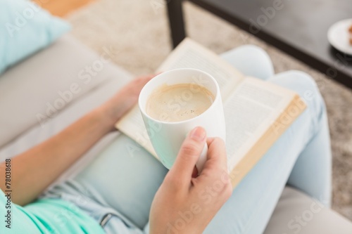 Woman reading and drinking coffee on couch