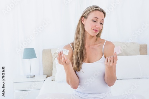 Woman choosing her medicine on bed