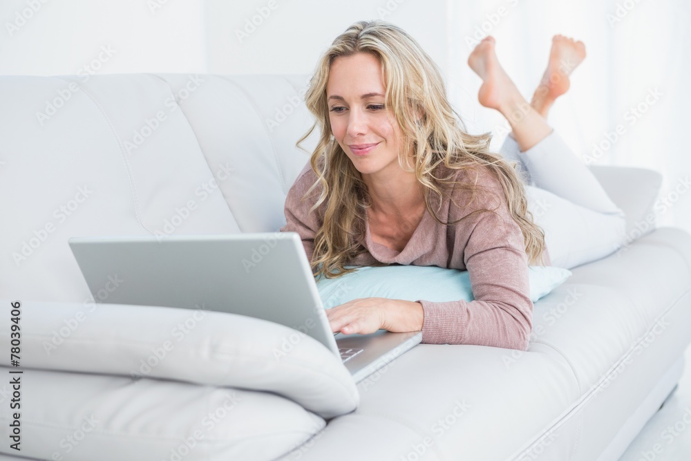 Pretty blonde lying on couch using laptop Pretty blonde lying on couch using laptop