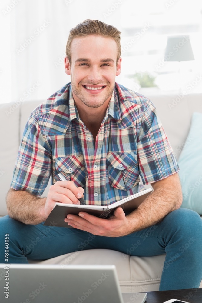 Smiling man on a laptop with a notebook Smiling man on a laptop with a notebook