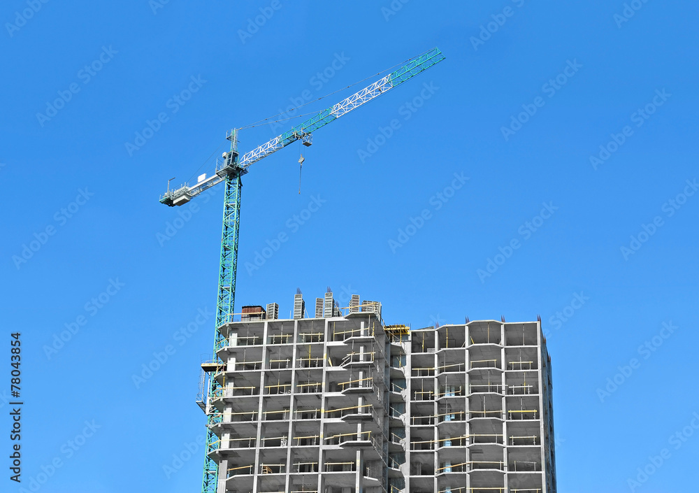 Fototapeta premium Crane and building construction site against blue sky