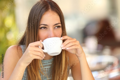 Woman drinking a coffee from a cup in a restaurant terrace