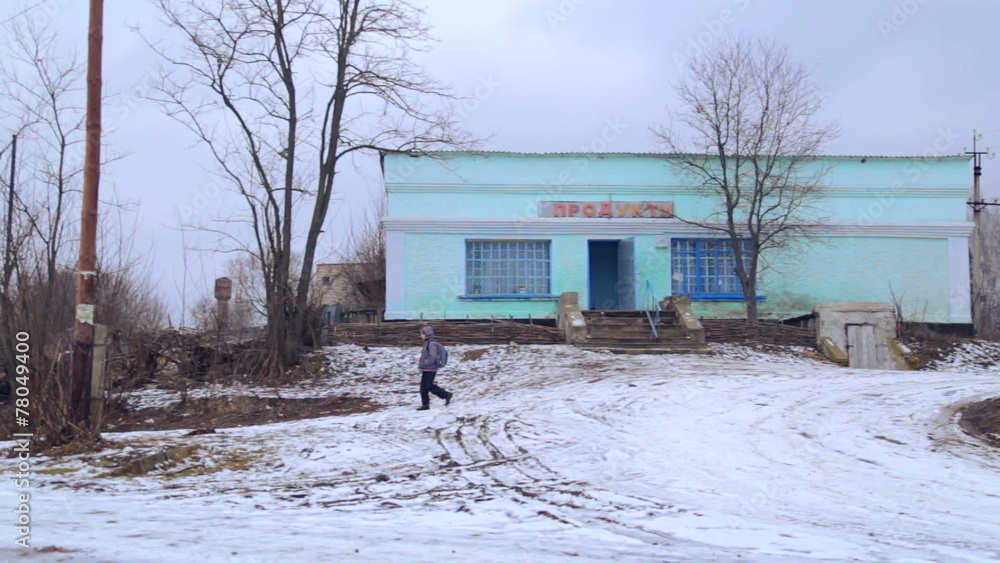 A teenager with a backpack goes on winter road in the village. A teenager with a backpack goes on winter road in the village.