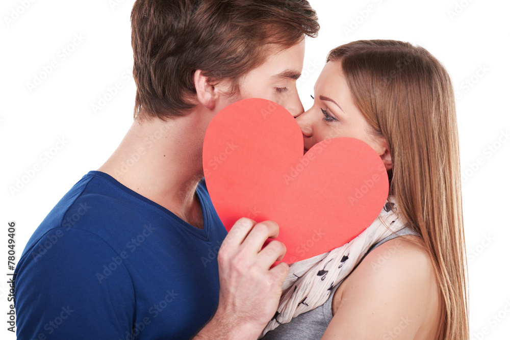 Woman and man kissing behind red heart