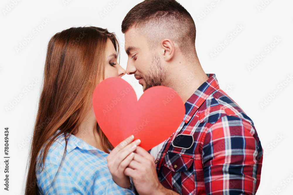 Young couple is kissing behind red heart