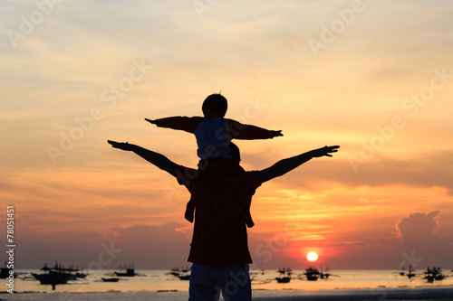 father and son having fun on sunset beach