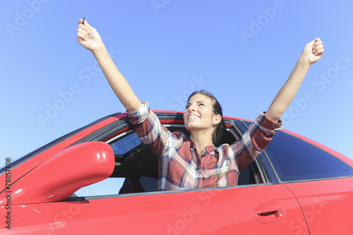 A beautiful woman sitting in her new car, holding the keys.
