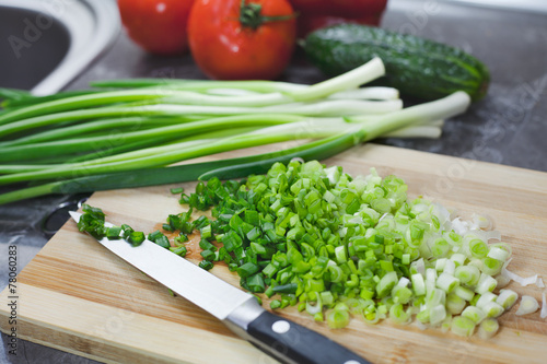 Chopped green onions and vegetables on striped wooden board