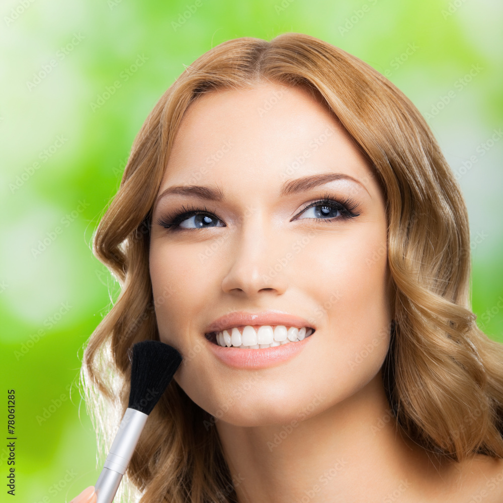 Woman with make up brush, outdoors Woman with make up brush, outdoors