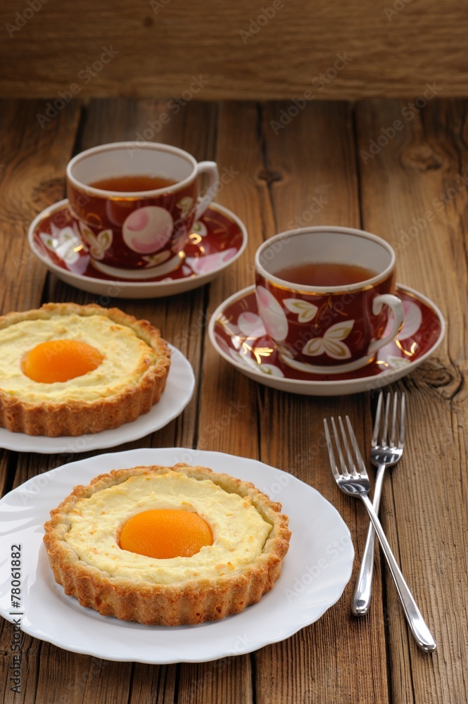 Peach tarts and cups of black tea on wooden background Peach tarts and cups of black tea on wooden background