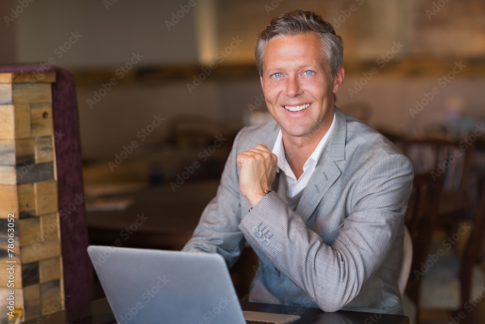 Fototapeta premium Smiling businessman using his laptop