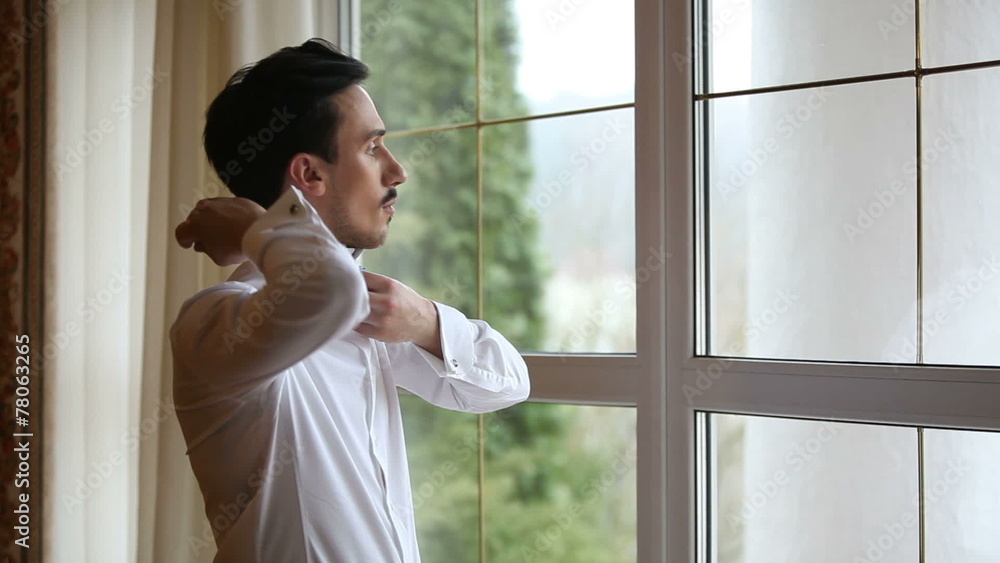 A man by the window wears bow tie A man by the window wears bow tie