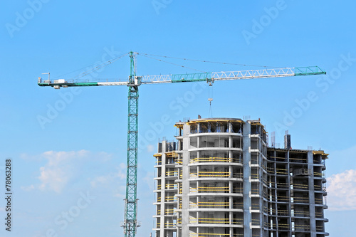 Crane and building construction site against blue sky