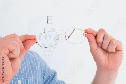 Hands holding glasses for eye test