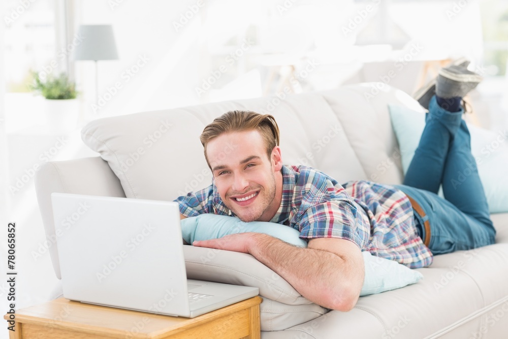 Happy man lying on sofa using laptop Happy man lying on sofa using laptop