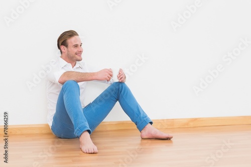 Casual man sitting on floor holding cup