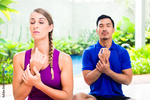 Mixed couple at yoga training in tropical Asia