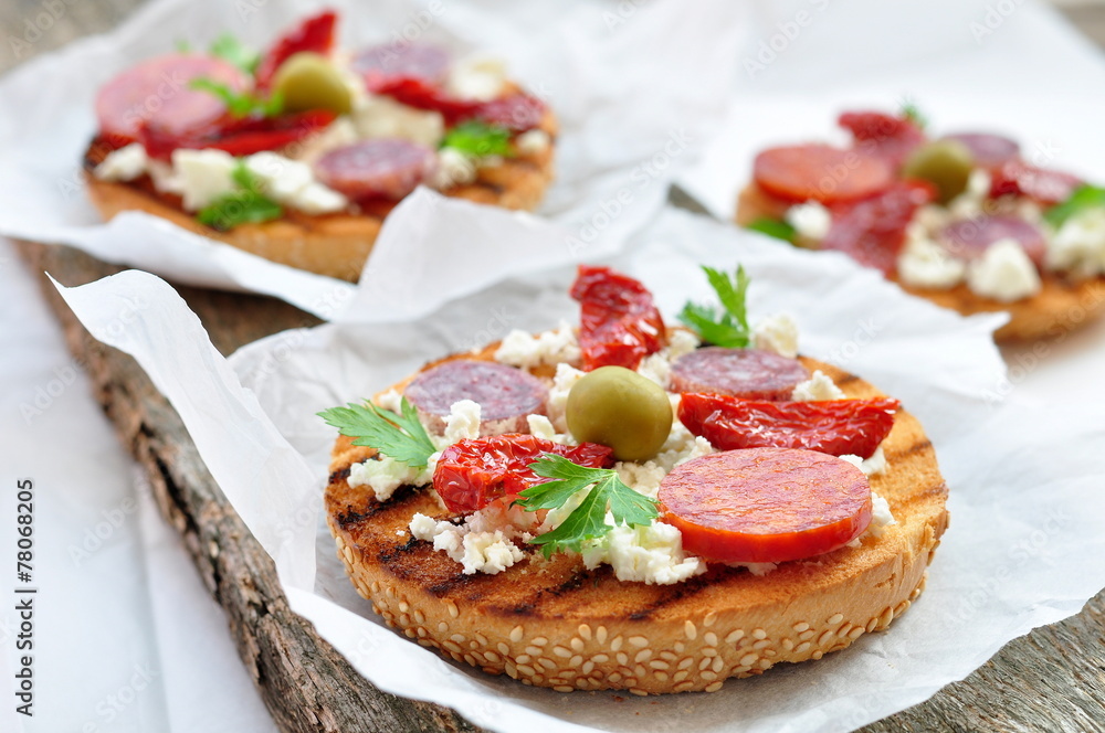 Toasts with dried tomatoes, pepperoni and ricotta