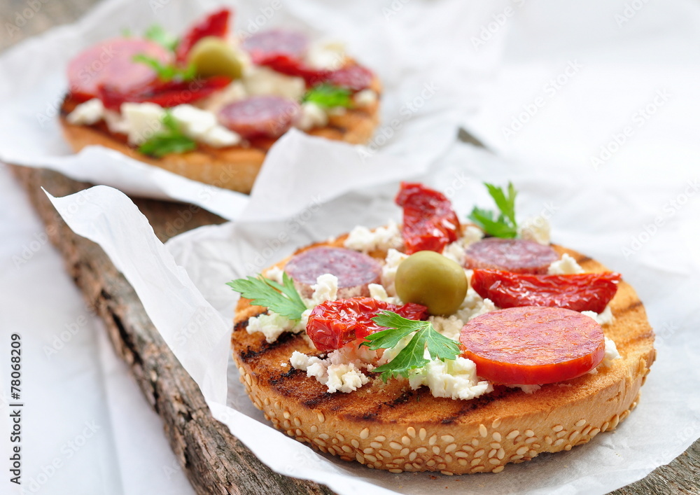Toasts with dried tomatoes, pepperoni and ricotta