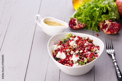 Healthy salad with pomegranate seeds, almond, feta cheese and photo