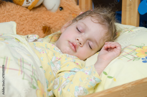 Three year old girl sleeping in her crib photo