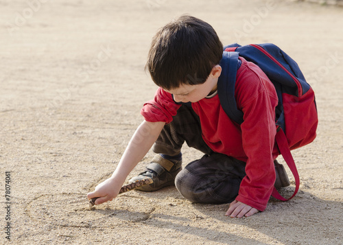 Child drawing into sand