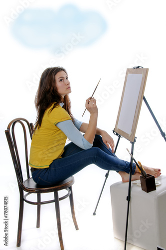Woman artist sitting before her easel thought