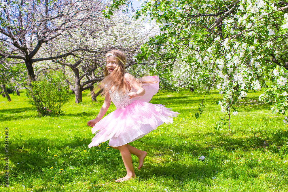 Adorable little girl have fun in blossoming apple tree garden Adorable little girl have fun in blossoming apple tree garden