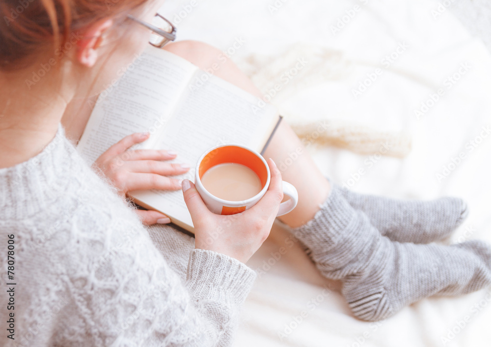 photo of a woman in a sweater with the old book and a cup of tea photo of a woman in a sweater with the old book and a cup of tea