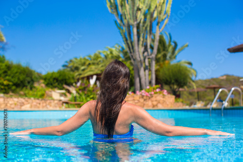 Beautiful young woman relaxing in swimming pool with cocktail